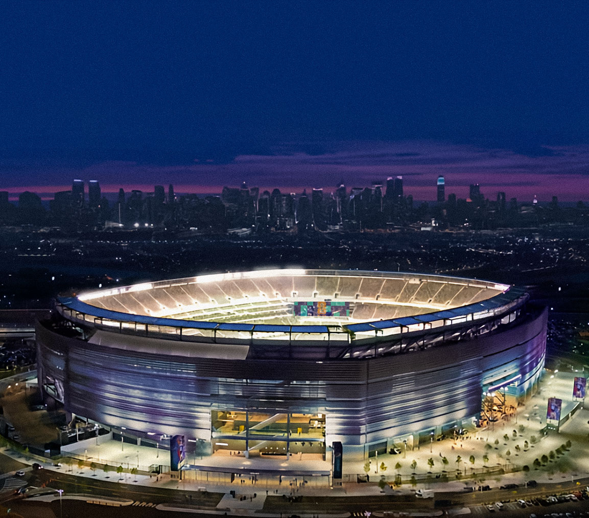 a World Cup Soccer venue with New York City in the backdrop as the sun sets below the horizon.