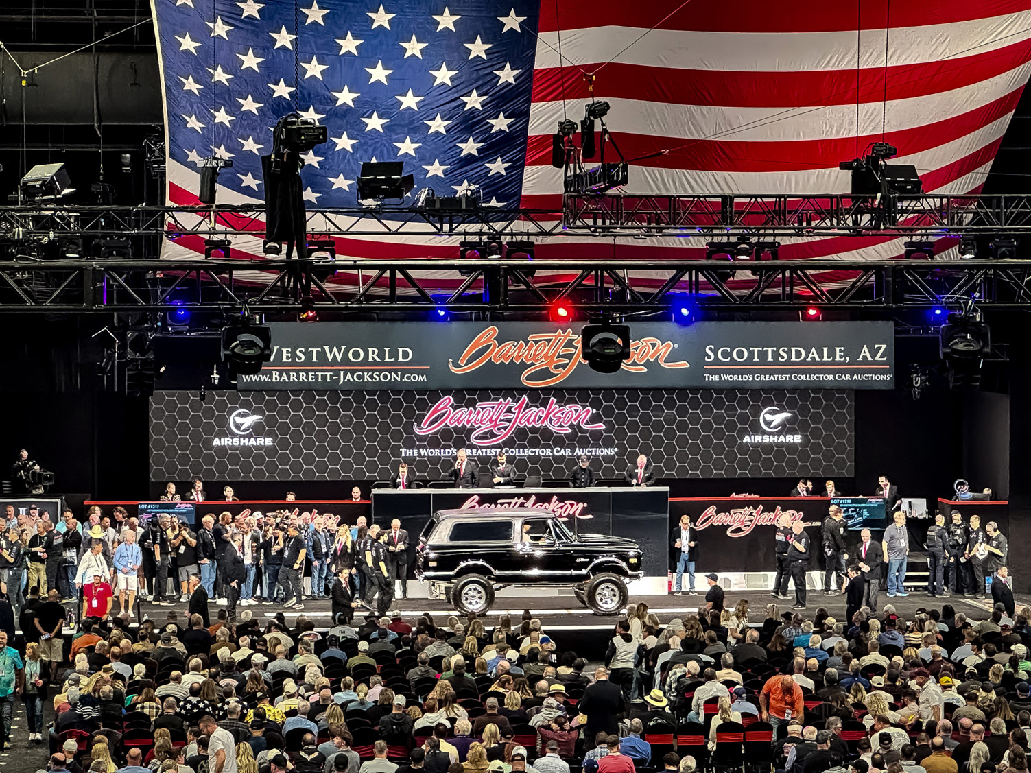 Barrett-Jackson Auction Block with Airshare partnership displayed on the screen behind a Ford Bronco that is on the clock for auction.
