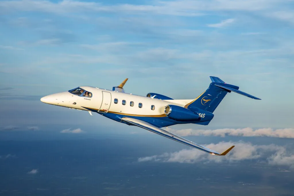 Airshare Phenom 300E in flight over clouds.